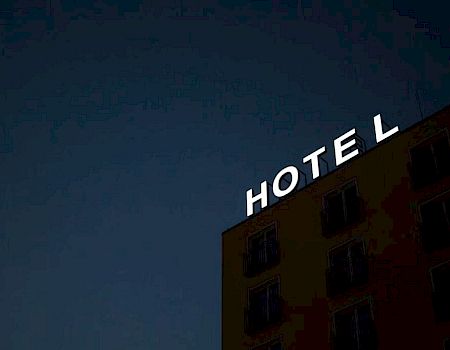 A dimly lit hotel building at night with an illuminated "HOTEL" sign on the rooftop.