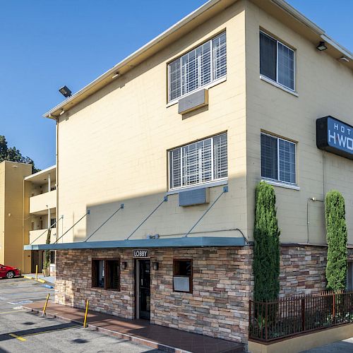 The image shows a multi-story beige building with a sign that reads 